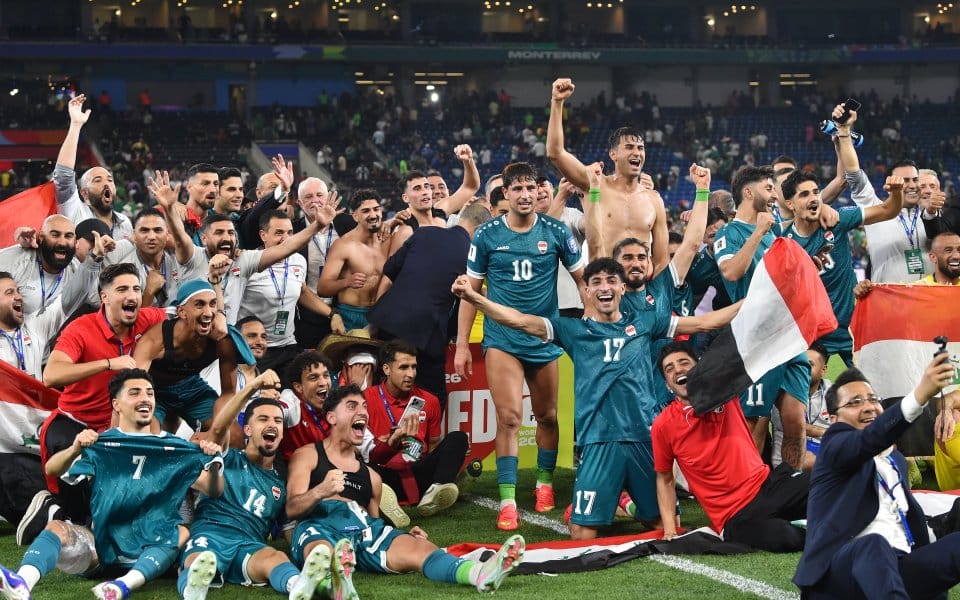 Egyptian football team celebrating victory on the field with fans in the background, waving a flag